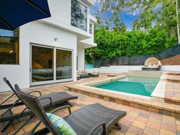 Backyard at Hill House with pool, fire pit, and patio seating at sunset.