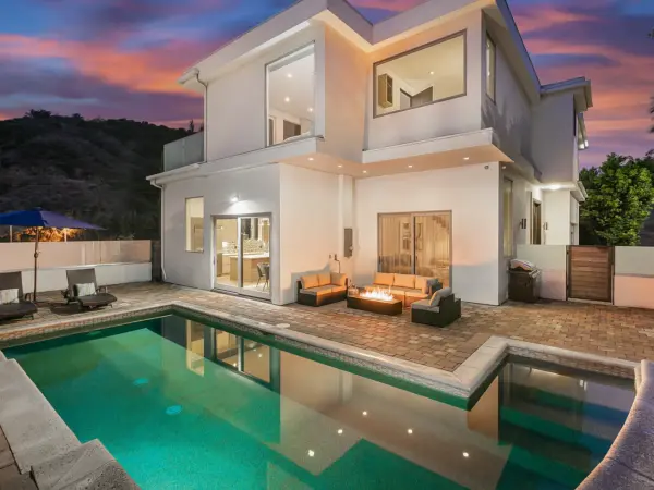 Hill House backyard featuring pool, fire pit, and panoramic hillside views at sunset.