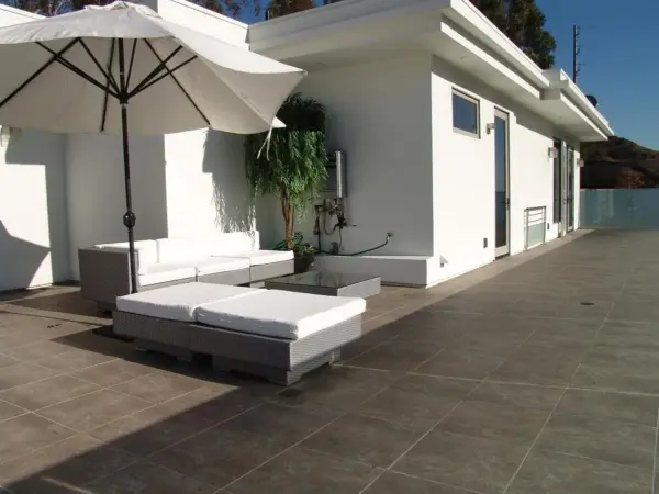 Hill House rooftop patio with white lounge seating and umbrella.